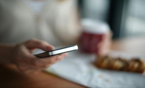 A man sitting on a bench uses his phone, illustrating the importance of text messaging for nonprofit engagement.